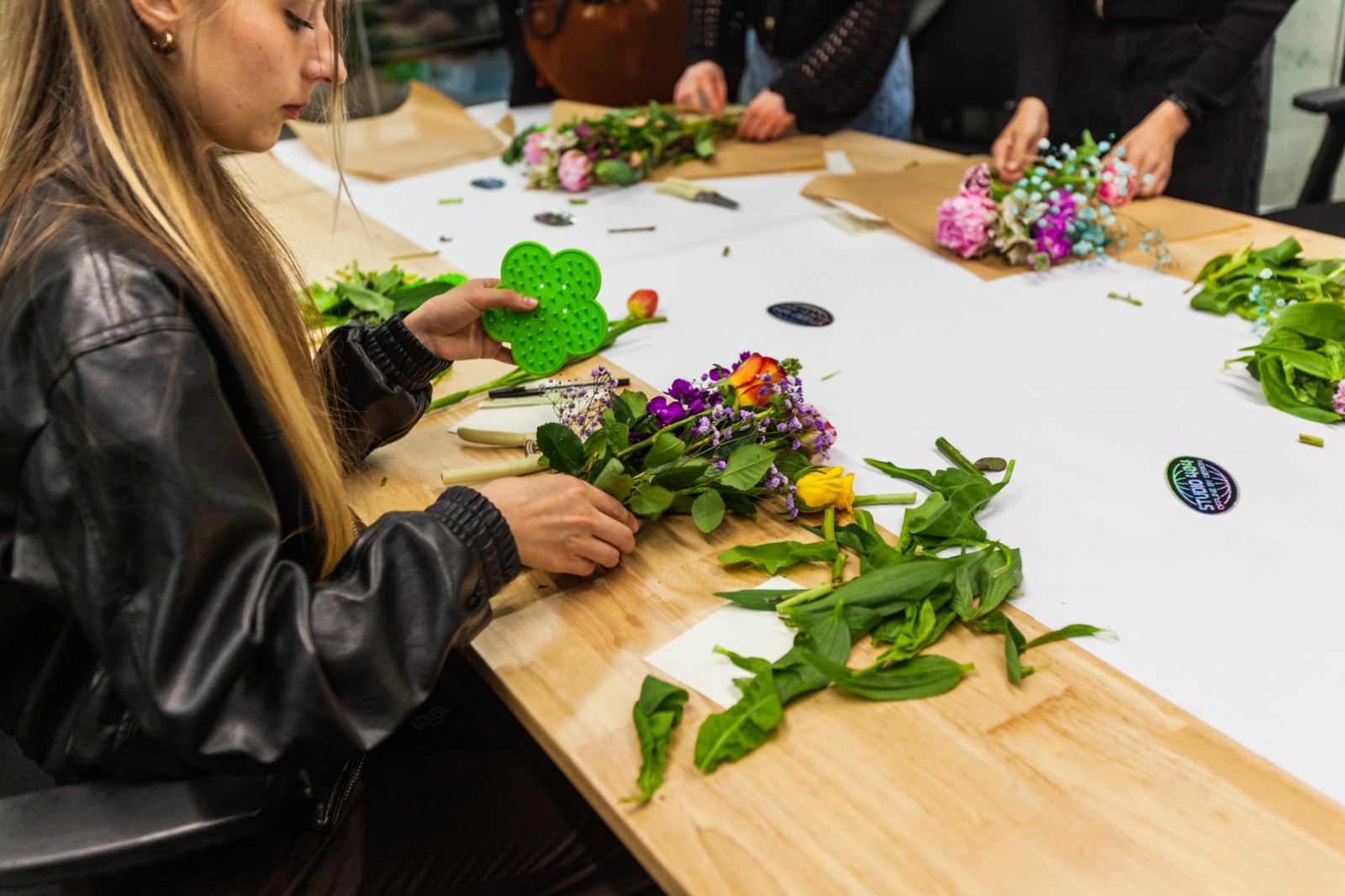 A guest arranging stems beside a green flower frog