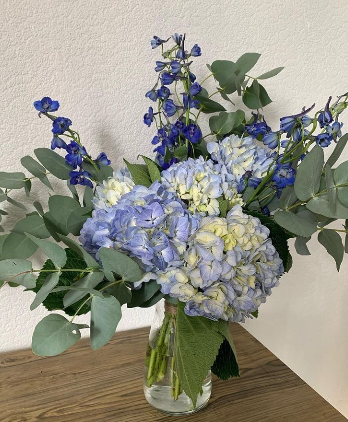 Blue hydrangeas, delphiniums and eucalyptus in a glass jar